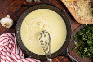 cheese added to butter mixture with a whisk in a skillet