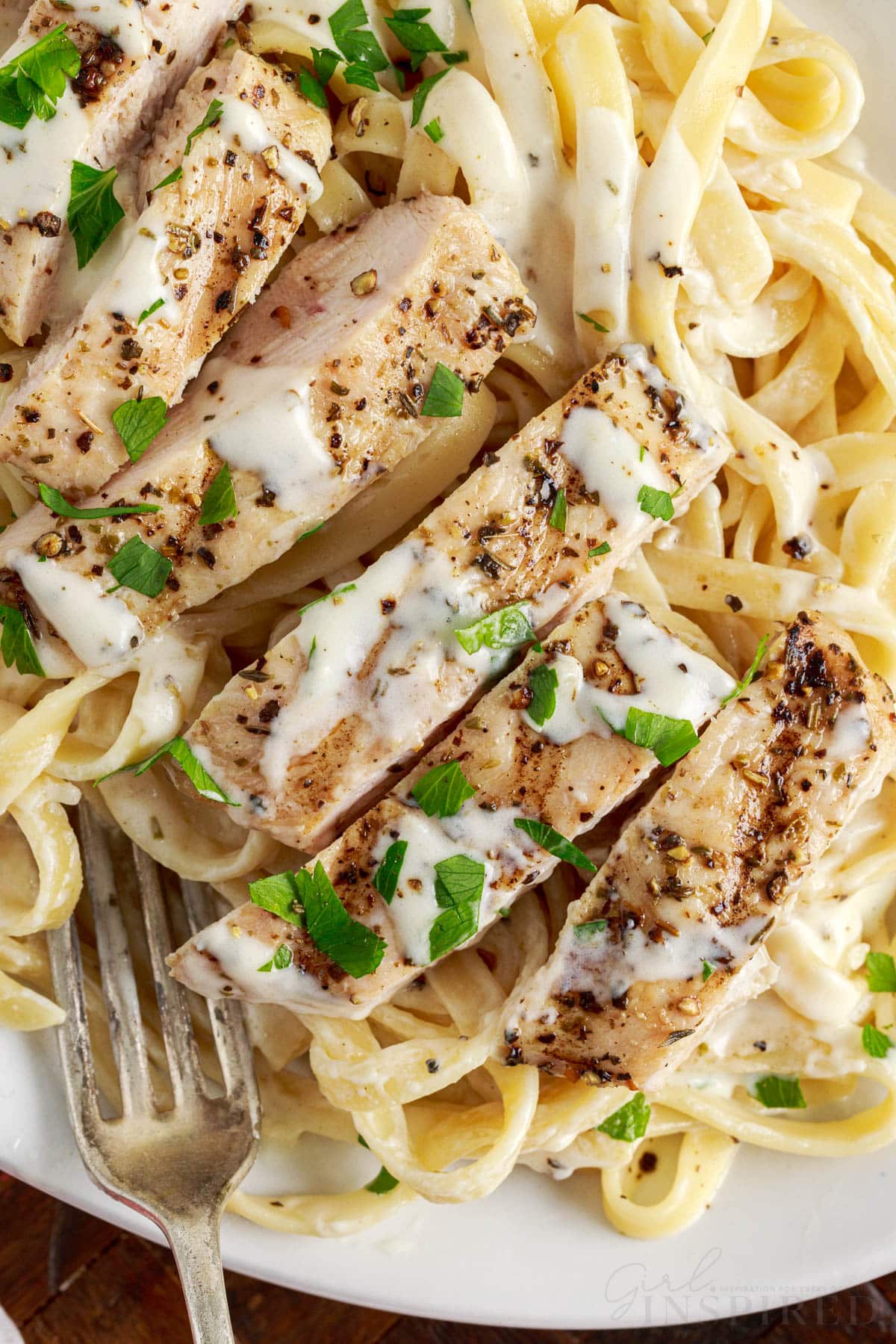 top view of grilled chicken alfredo on a plate with a fork on it