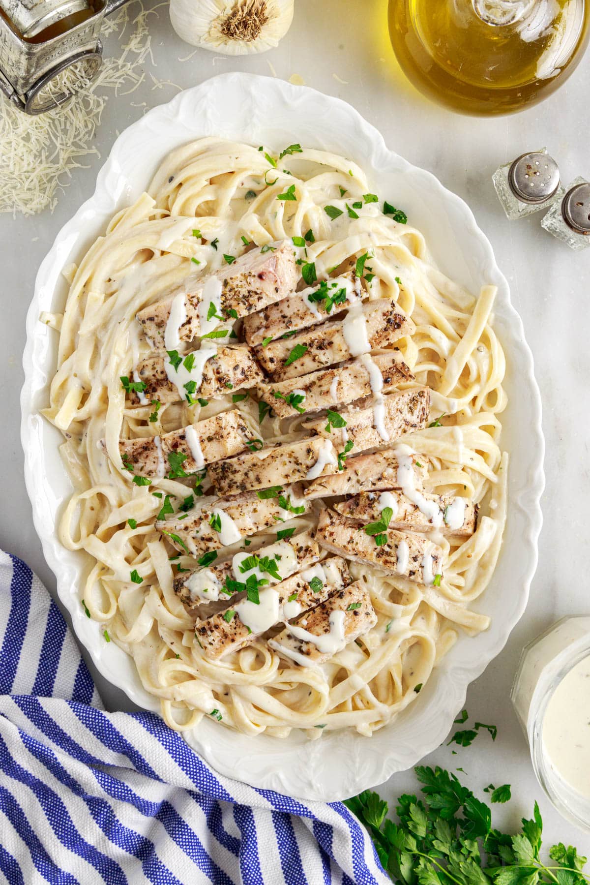top whole view of oval white plate of grilled chicken alfredo