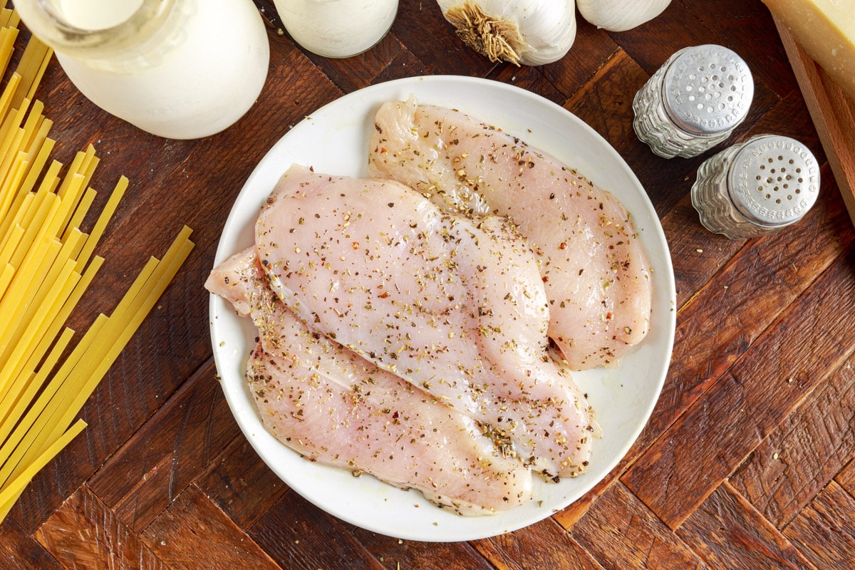 seasonings and olive oil rubbed into chicken breasts on a plate