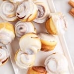 top view of multiple mini cinnamon rolls on an off a white platter