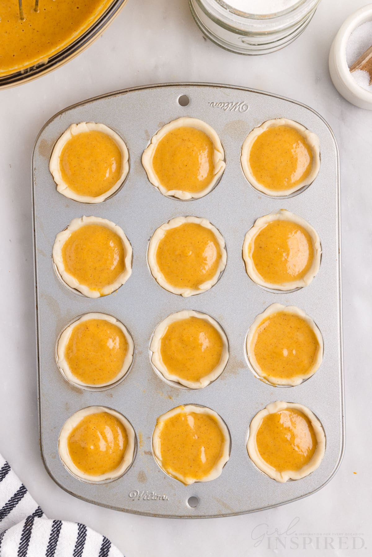 muffin tin filled with pumpkin filling