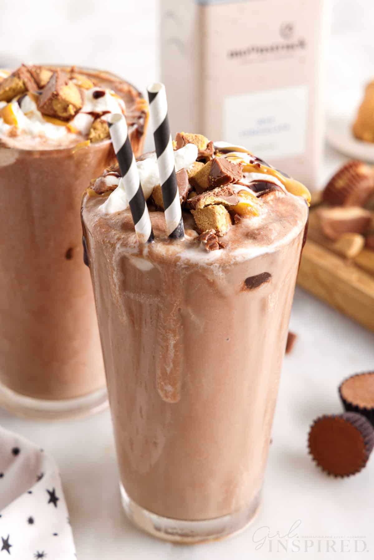 glasses of peanut butter frozen hot chocolates two white and black striped straws in the front one