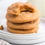 stack of pumpkin butterscotch cookies on white plates with a bite taken out of top cookie.