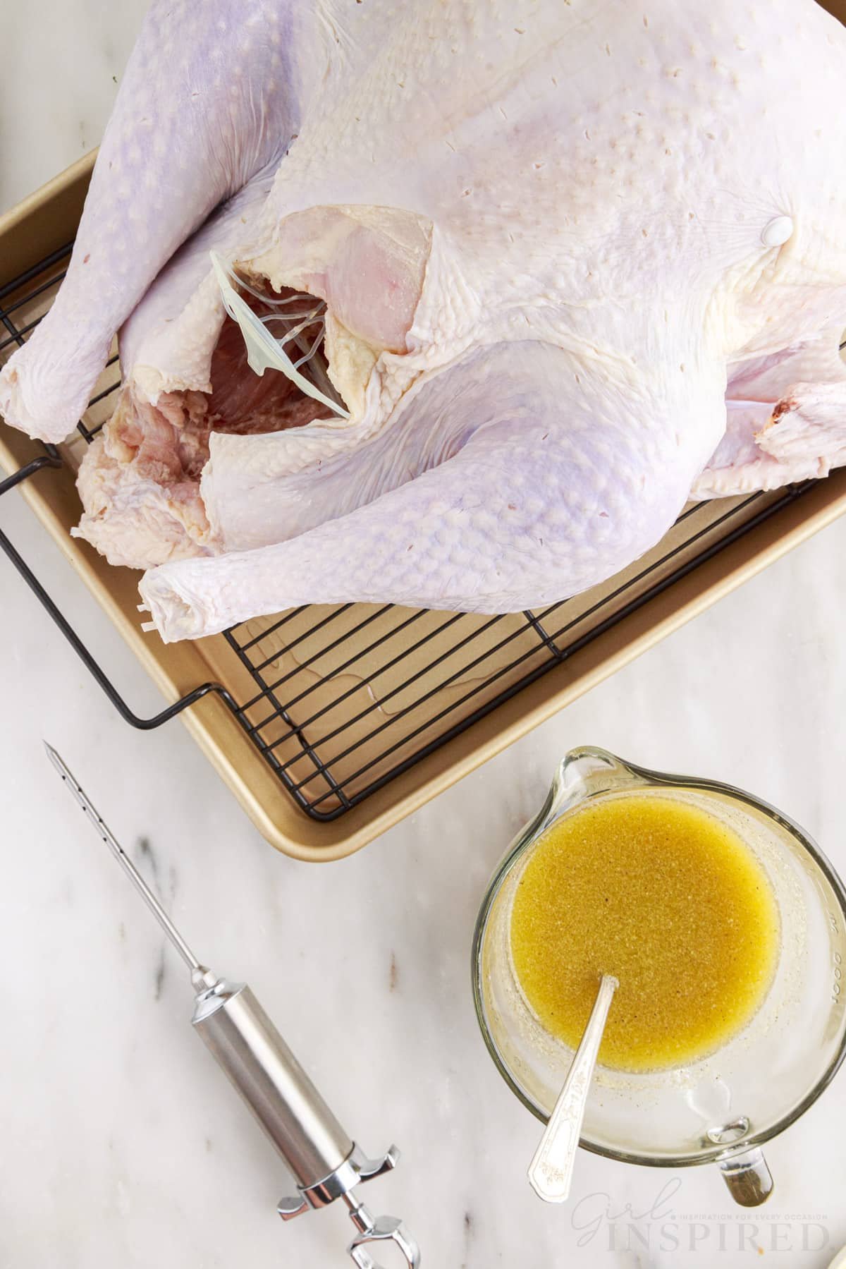 turkey in a roasting pan next to injector and measuring cup with smoked turkey injection ingredients