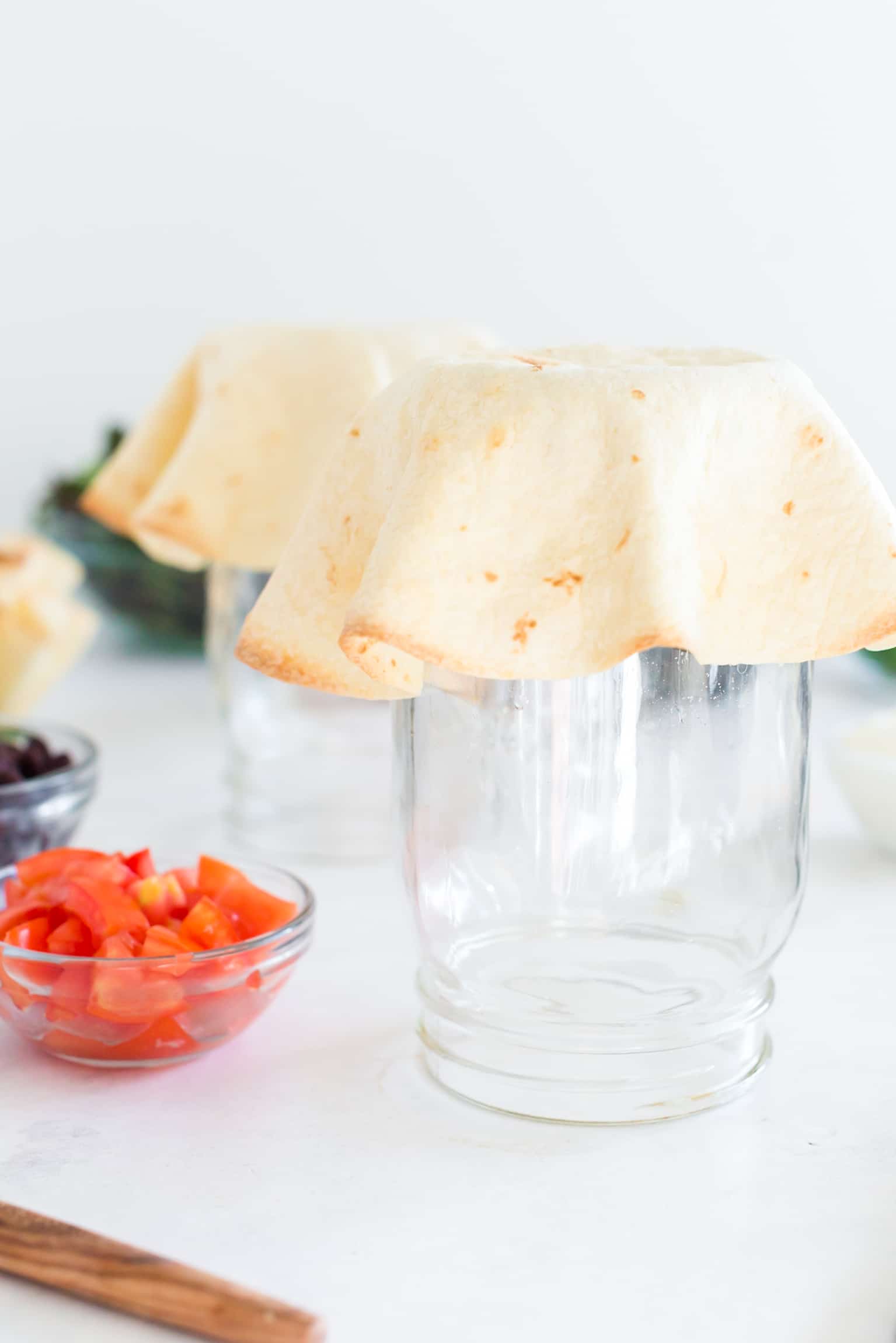 cooked taco shell draped upside down over large mason jar.