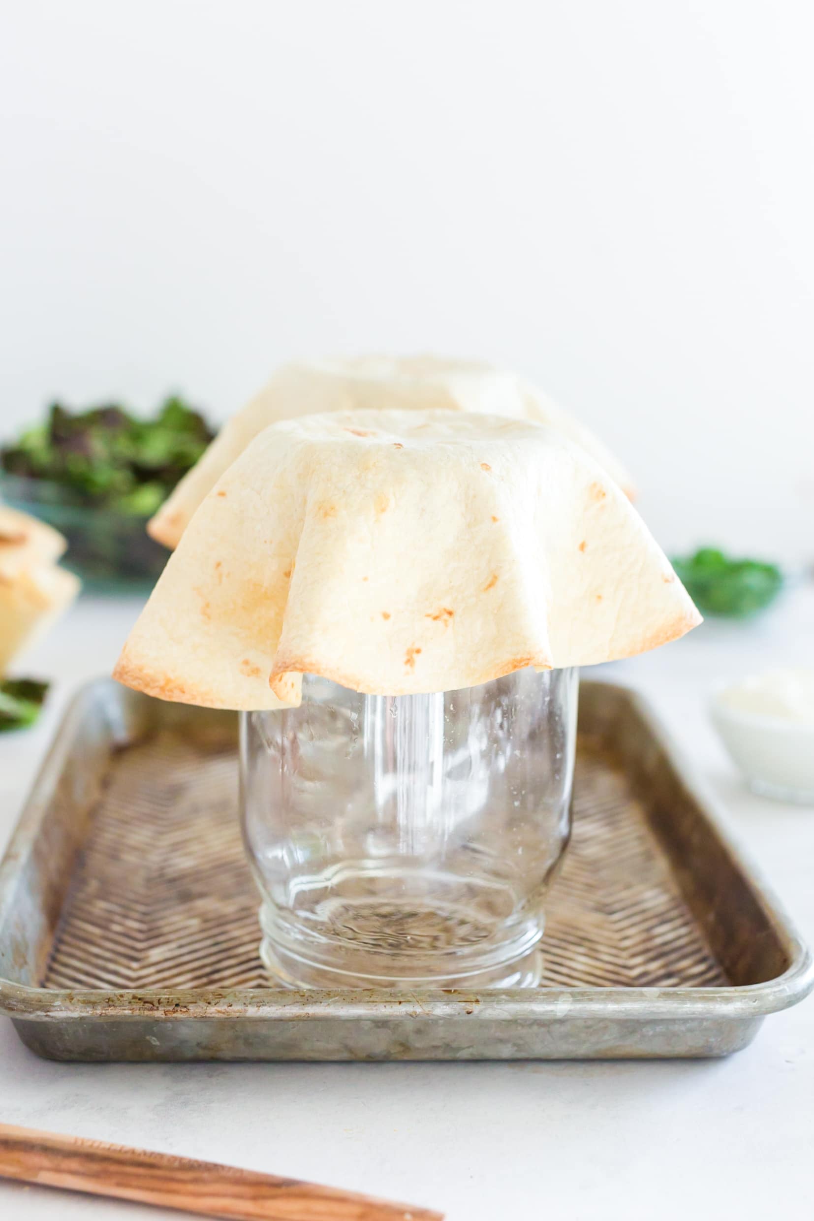 baked tortilla bowl with golden edges draped over upside down mason jar.