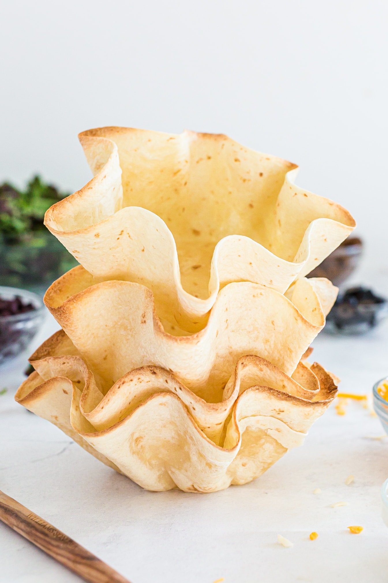 golden taco shell bowls stacked on top of each other.