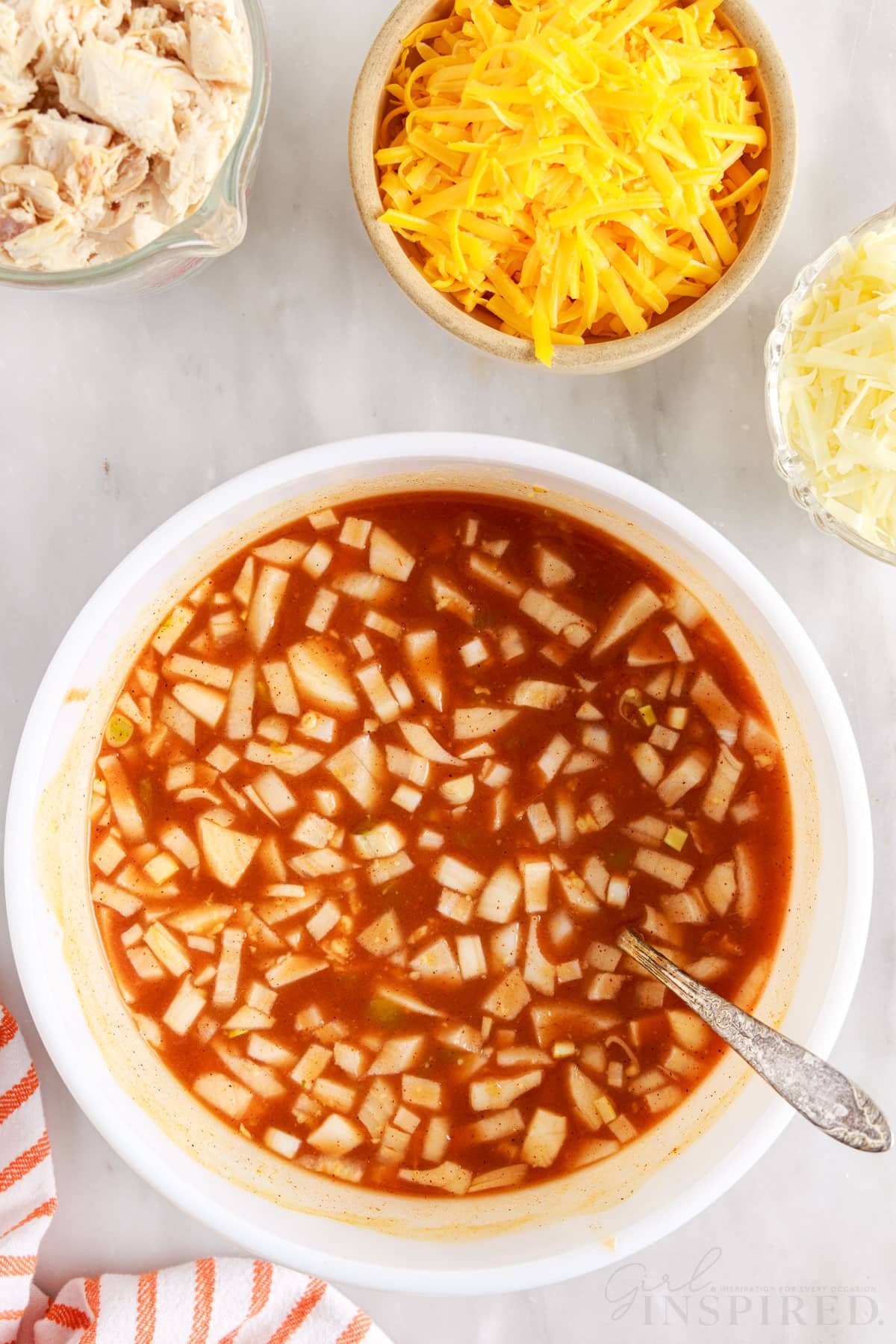 turkey enchilada sauce mixture combined in a mixing bowl with spoon