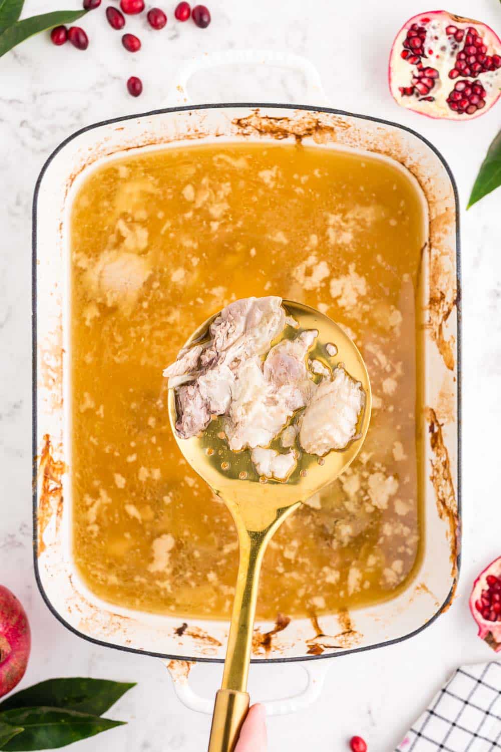 chunks of meat being taken out of drippings with a large slotted spoon