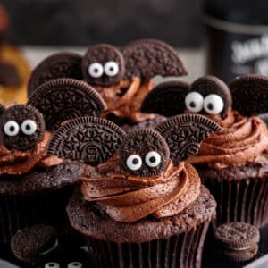Chocolate cupcakes decorated with bats made from Oreo cookies and candy eyeballs.