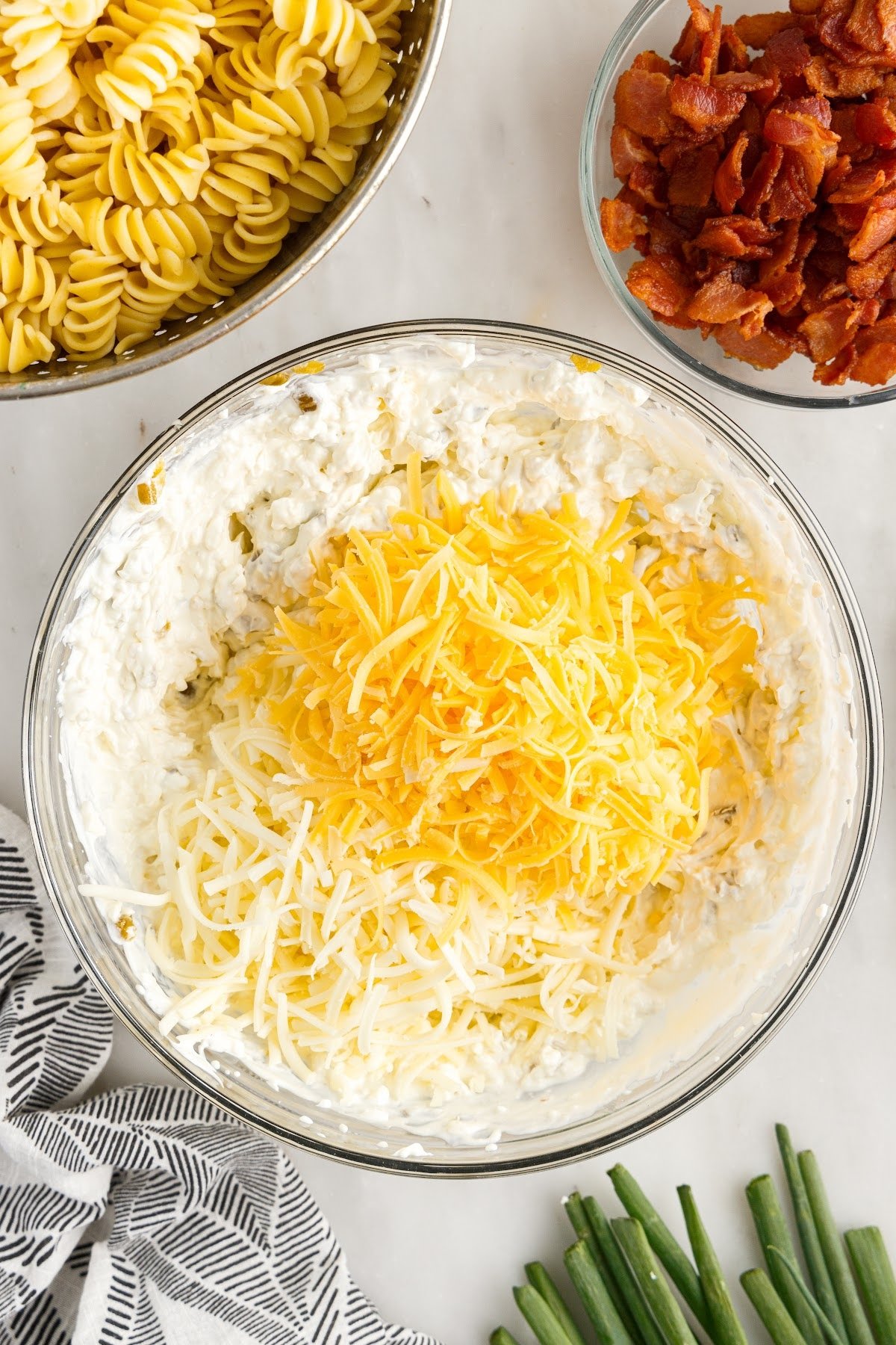 Grated cheeses being mixed into the cream cheese mixture.