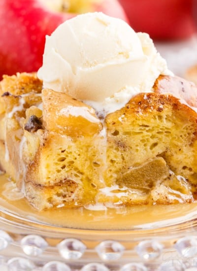 a piece of apple bread pudding with caramel sauce and a scoop of ice cream on top, served on a glass plate