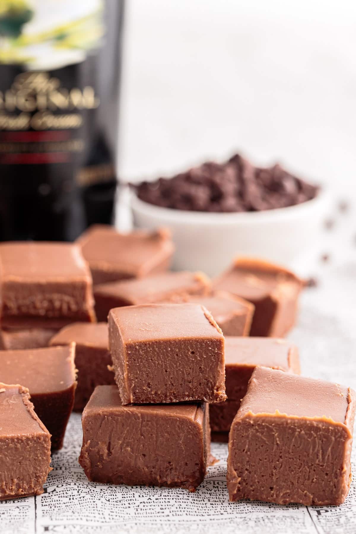 front view of cubed baileys fudge pieces with baileys bottle and chocolate chips in the background