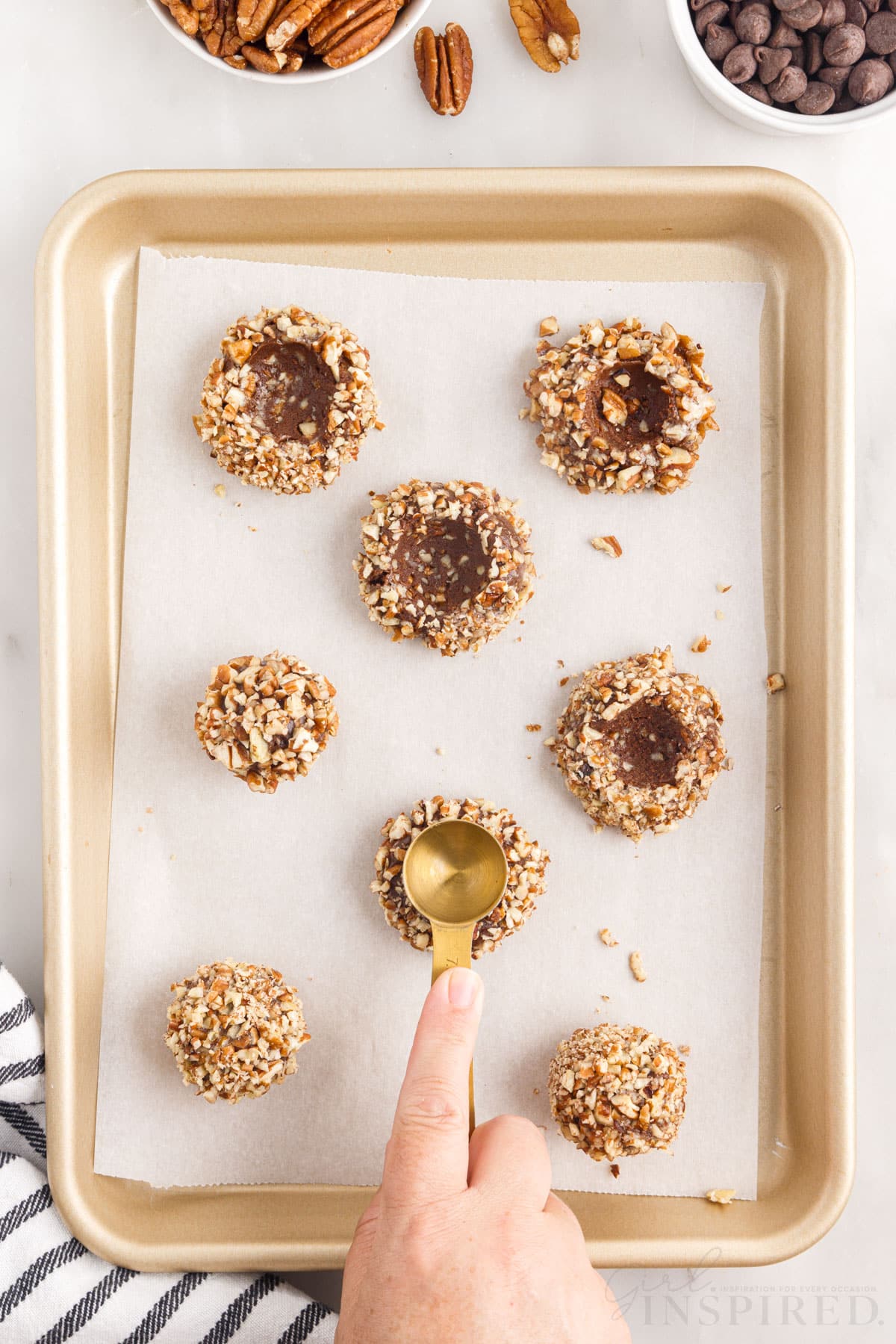 teaspoon pressing holes in the center of chocolate turtle thumbprint cookie dough balls