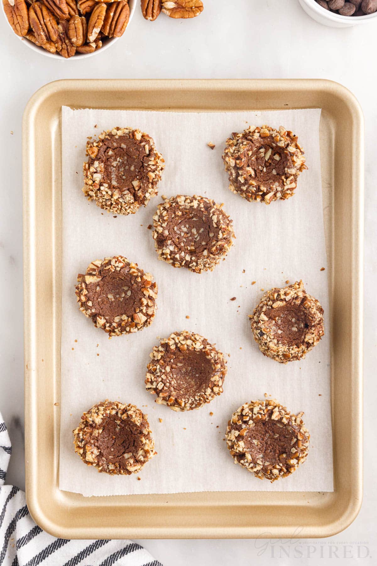 a cookie sheet of baked chocolate turtle thumbprint cookies
