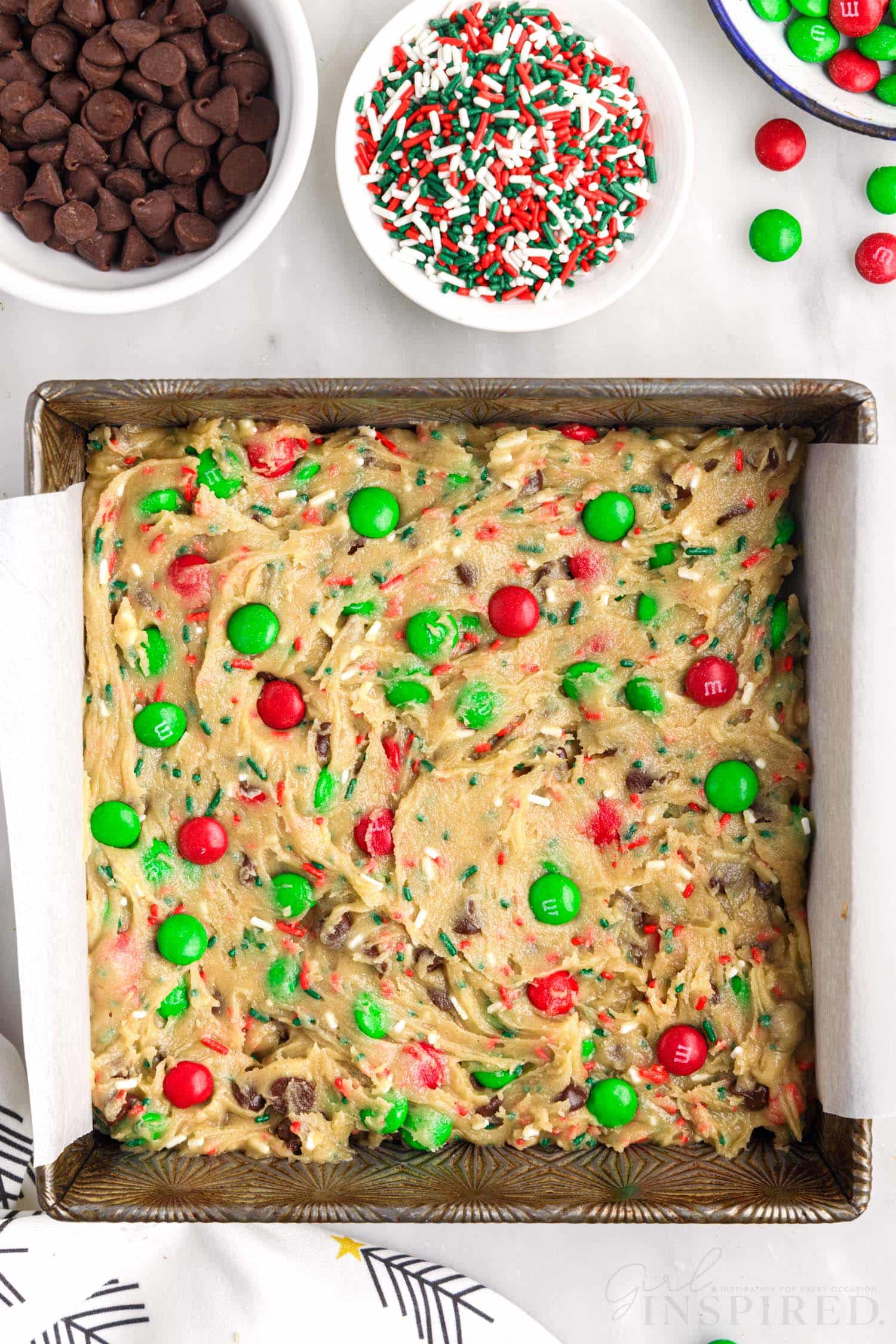 8x8 parchment lined pan filled with christmas bar cookie dough