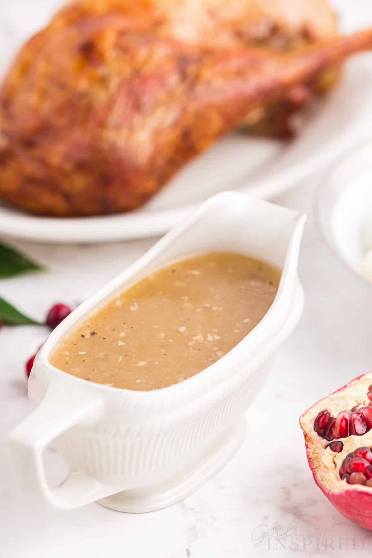 gluten free turkey gravy in white gravy boat with turkey in background