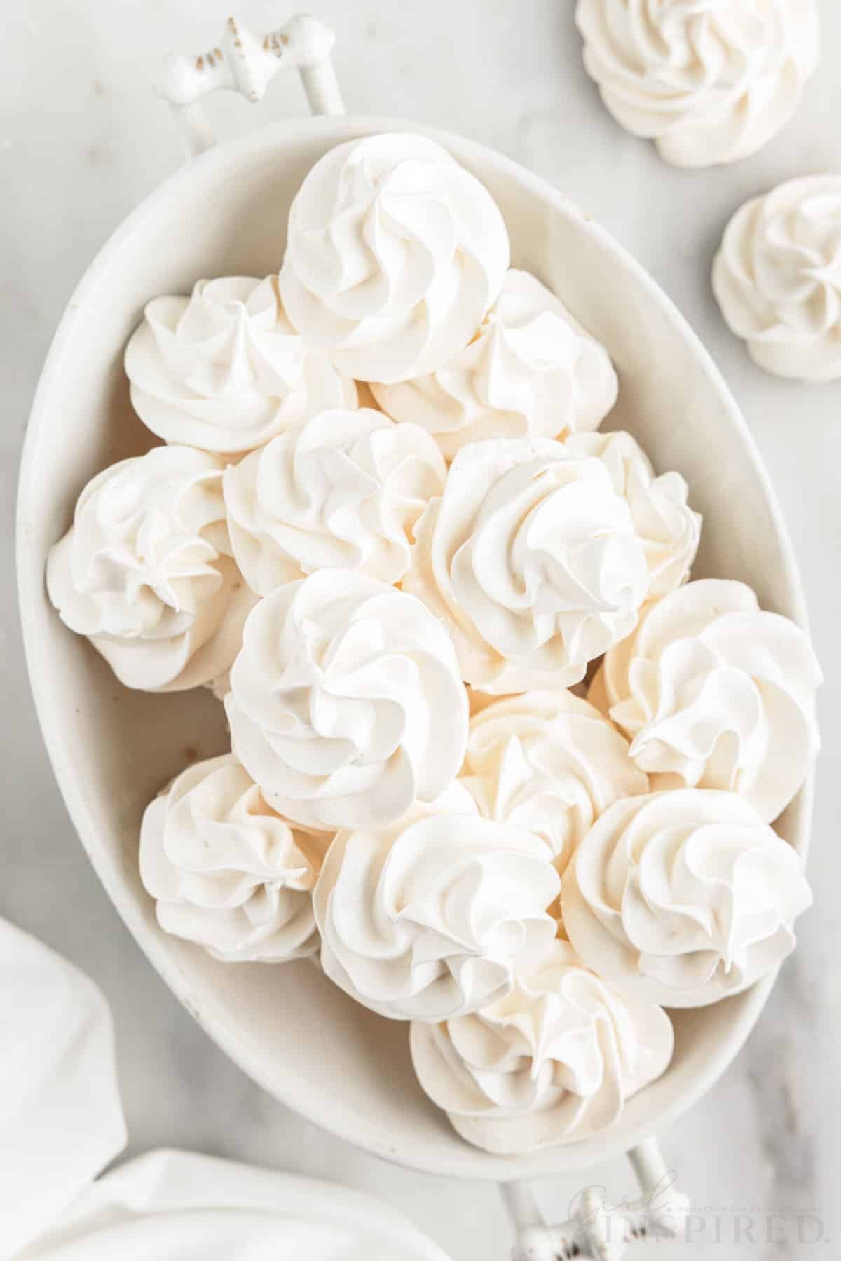 oval white serving bowl with meringue cookies stacked in it