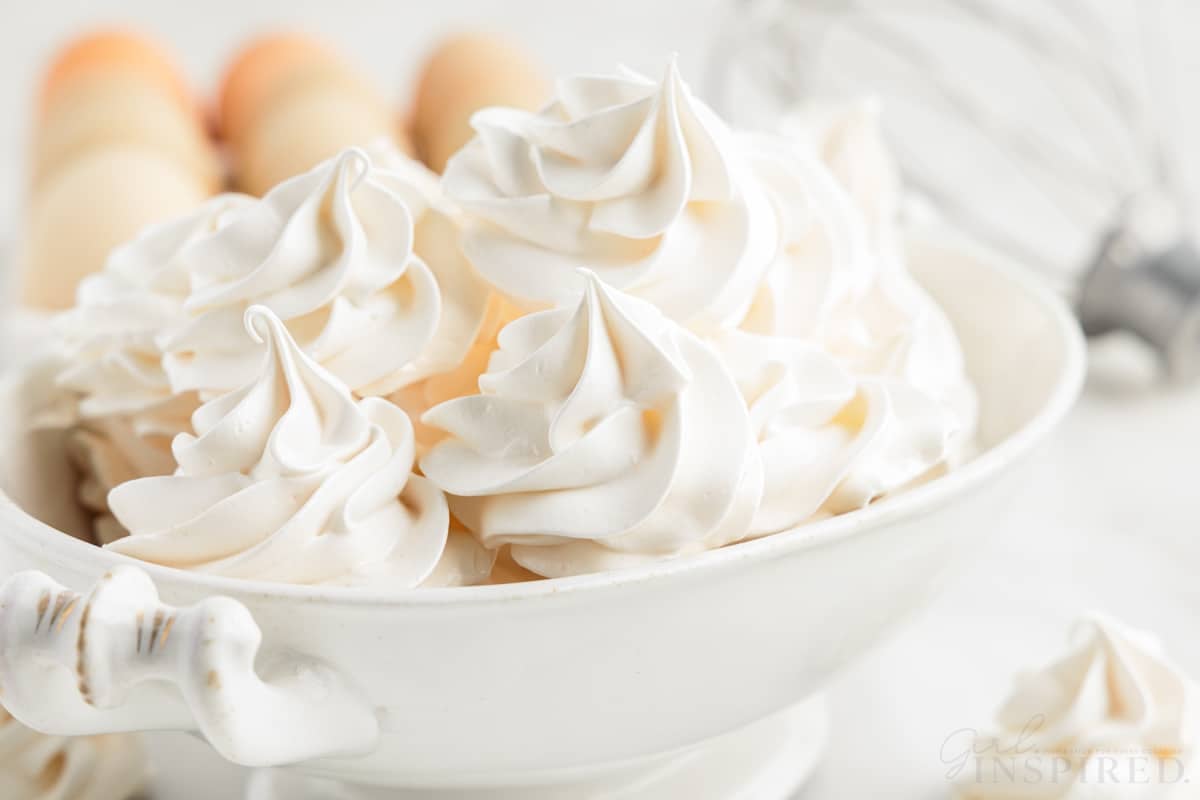 front view of a bowl of meringue cookies with eggs in the background