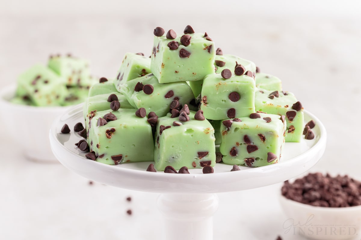 tiered tray full of mint chocolate chip fudge pieces with a bowl of chocolate chips and a bowl of fudge in the background