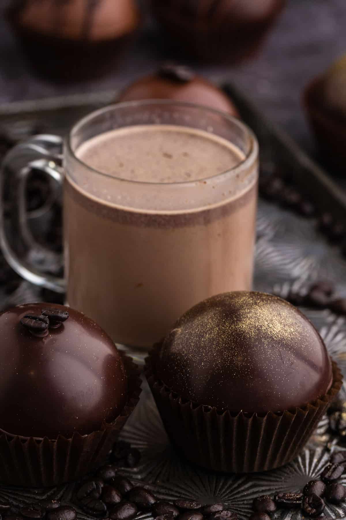 mocha hot chocolate bombs with a cup of hot chocolate in the background