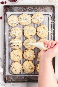 piping bag drizzling white chocolate on top white chocolate cranberry cookies