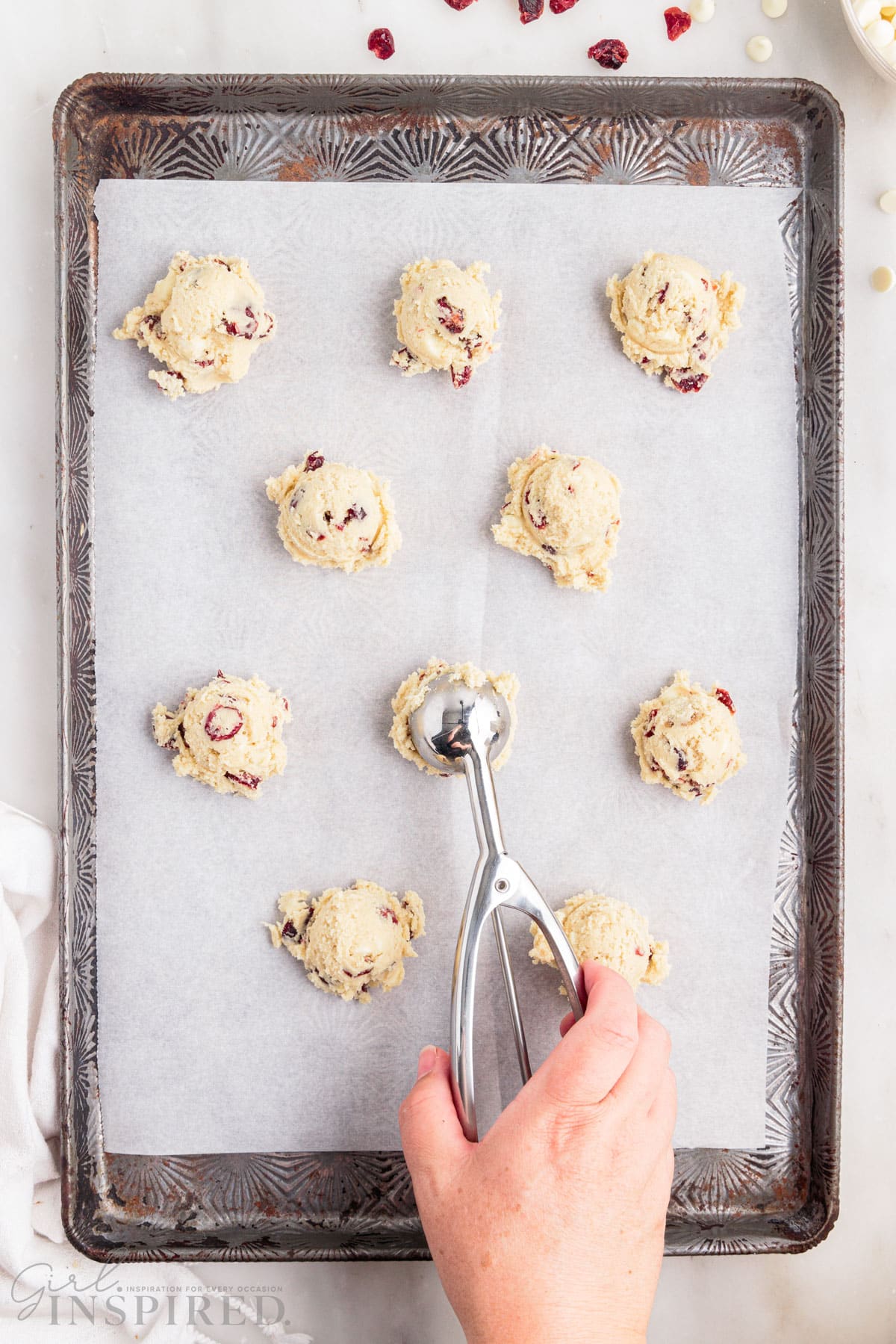 cookie scoop scooping balls of dough on parchment lined cookie sheet