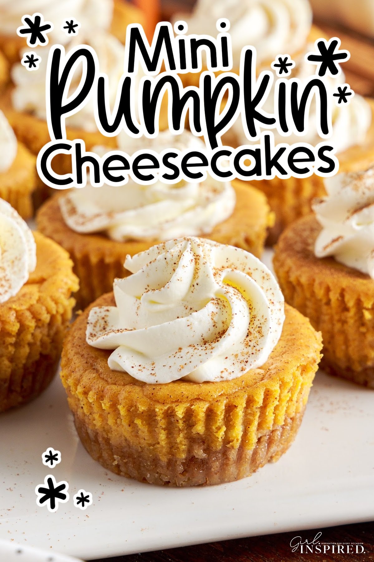 Mini pumpkin cheesecakes on white serving platter, topped with whipped cream, and text title.