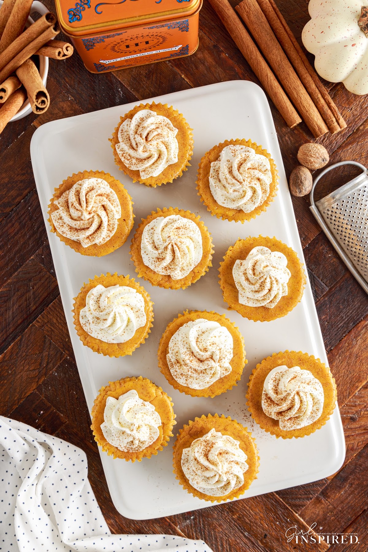 Mini pumpkin cheesecakes arranged on a white serving platter, view from above.