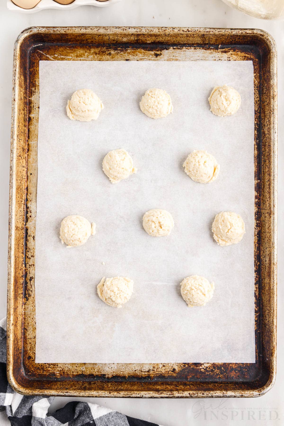 amish sugar cookie dough rolled into balls on a parchment paper lined cookie sheet