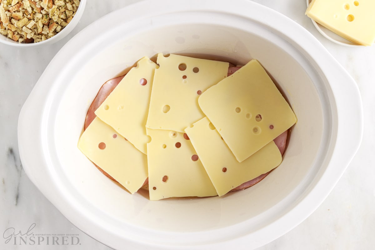 swiss cheese layered on top of ham slices in crockpot