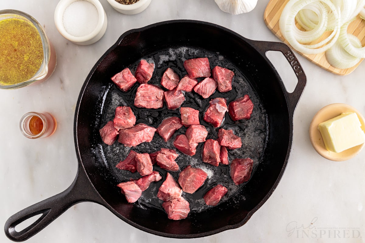 steak pieces added to skillet next to ingredients