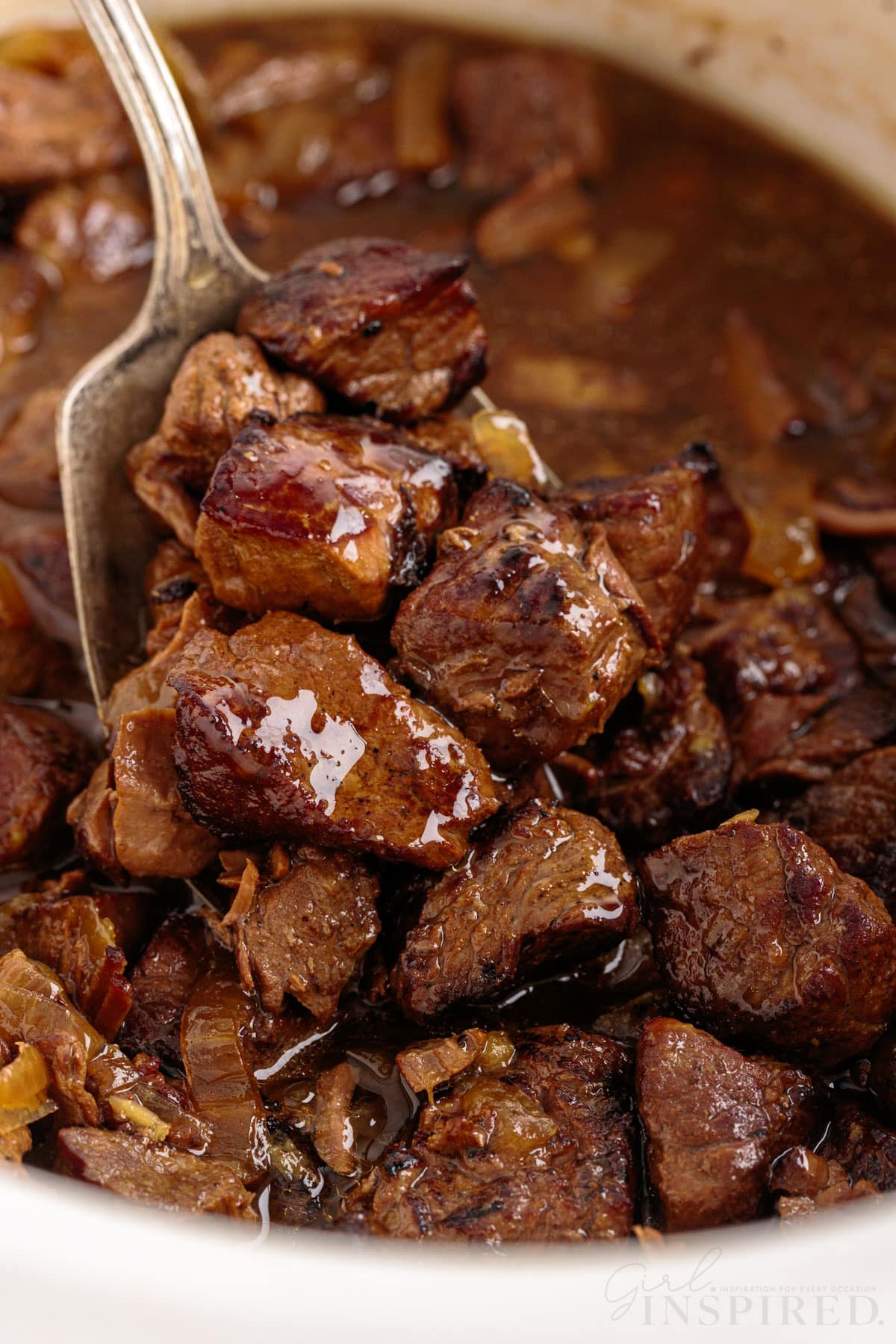 close up of spoon lifting cooked crockpot steak bites