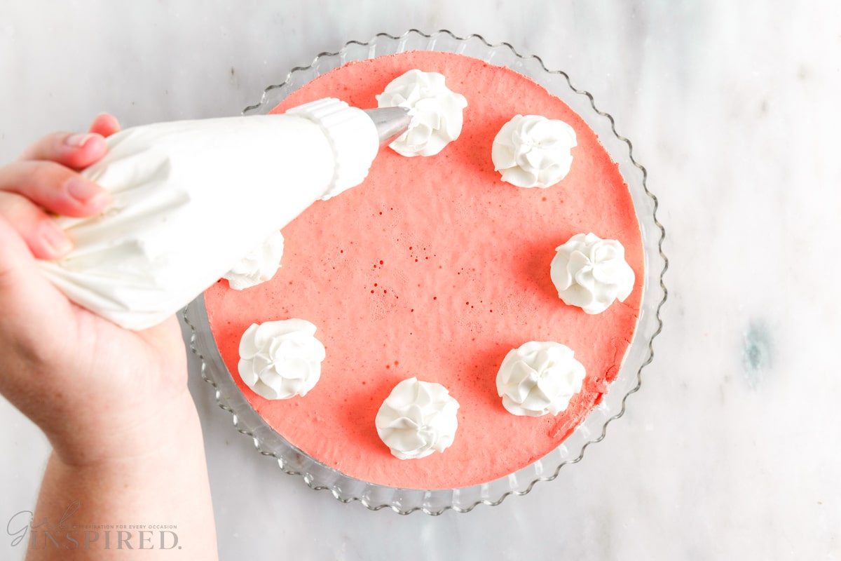 cool whip dolloped to the top of layered jello pie with a piping bag