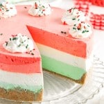 layered jello pie on a glass platter with a slice missing