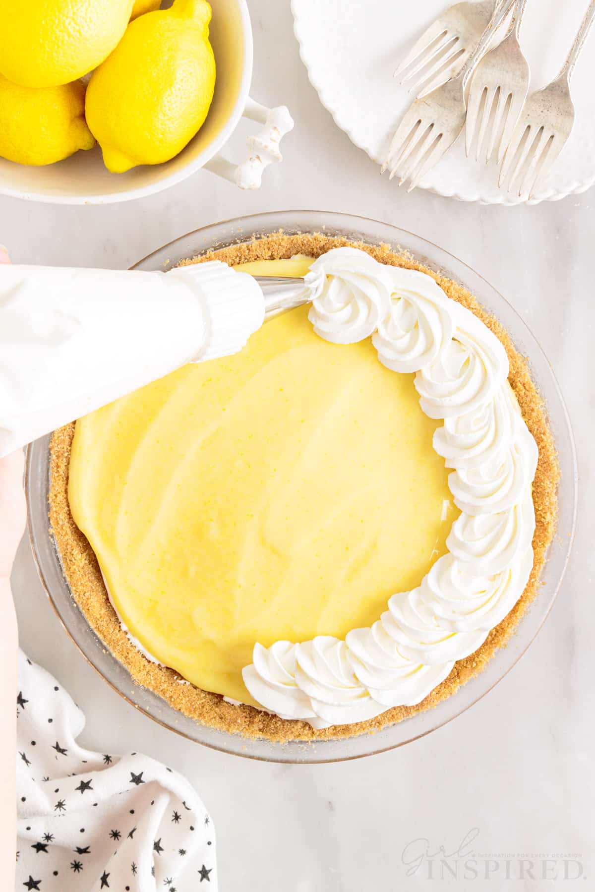 dollops of whipped cream piped onto lemon cream cheese pie with a piping bag