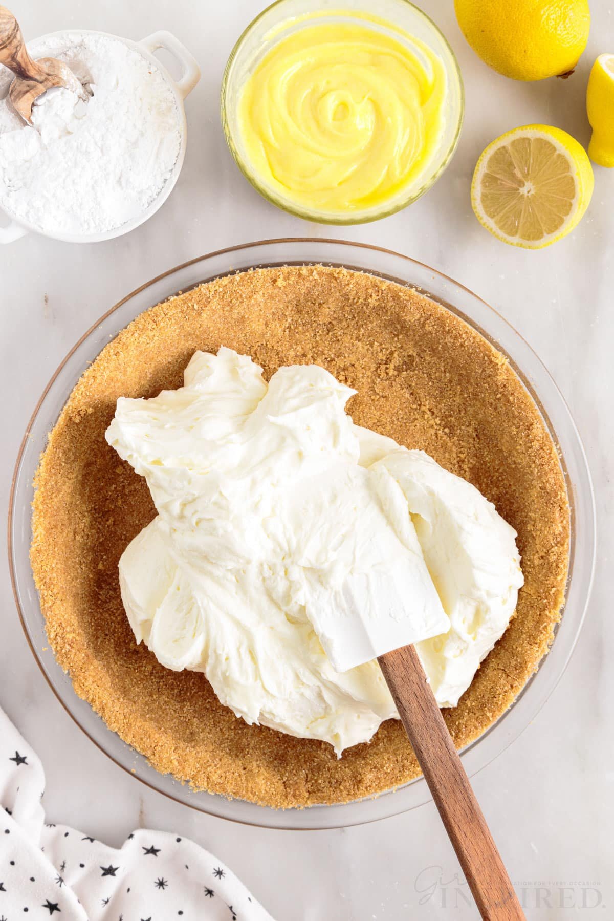 lemon cream cheese pie filling spread into a pie crust with a spatula in a glass pie dish