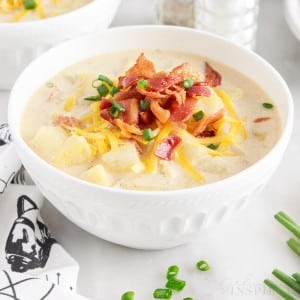 a small bowl of loaded baked potato soup topped with cheese onions and chives