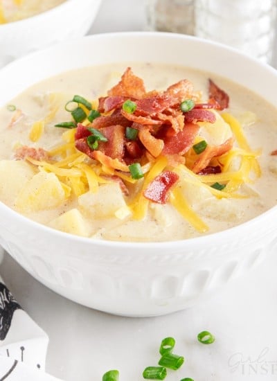a small bowl of loaded baked potato soup topped with cheese onions and chives