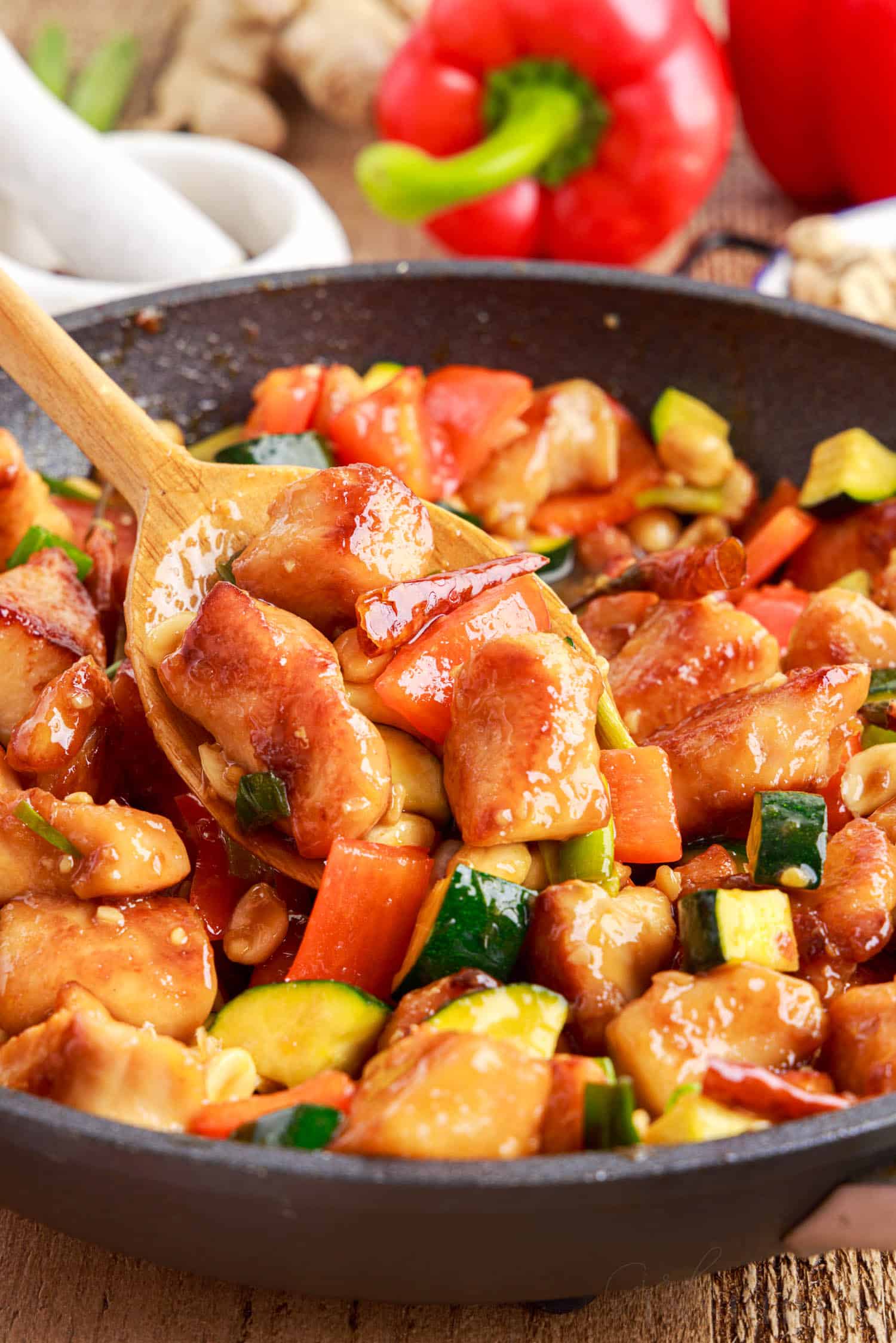 wooden spoon stirring panda express kung pao chicken in a skillet