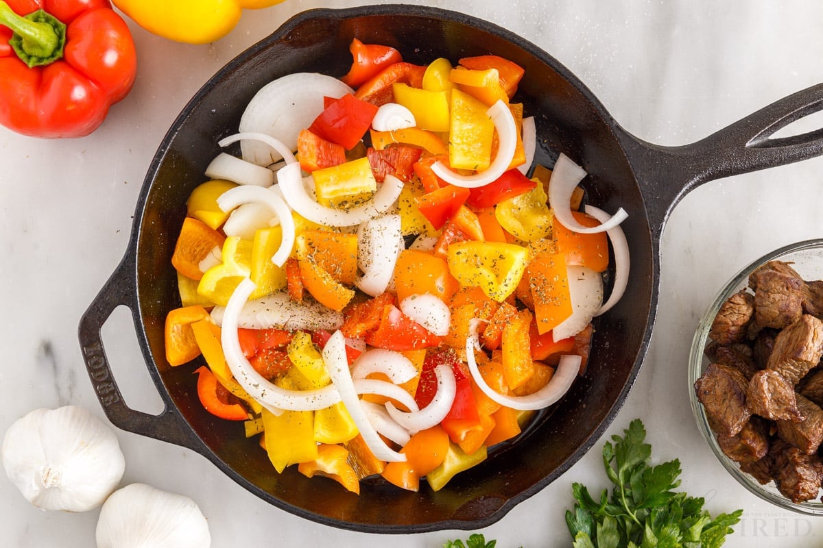 red orange yellow peppers and onions in skillet to make steak with peppers and onions
