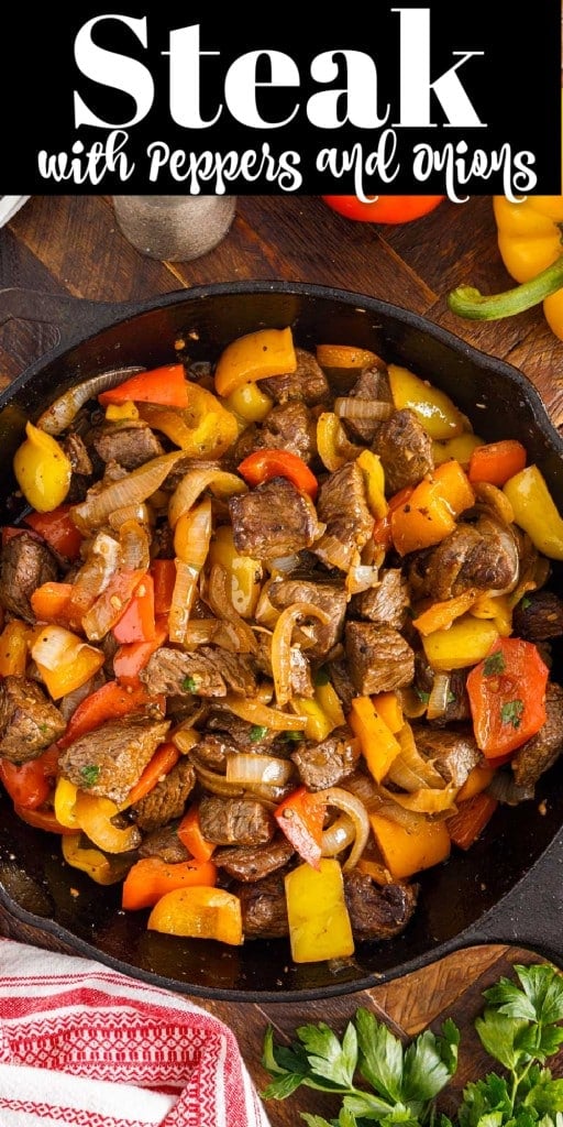 Steak with Peppers and Onions in a skillet on top of a wooden kitchen counter