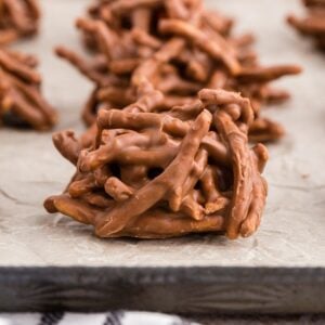 Piled chocolate butterscotch haystack cookies mounded on parchment paper on a baking sheet.