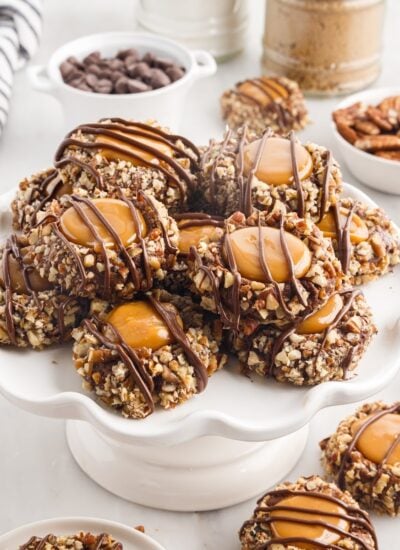 Top view of a stack of Chocolate Turtle Thumbprint cookies, showing the caramel filling and chocolate drizzle, with text overlay.