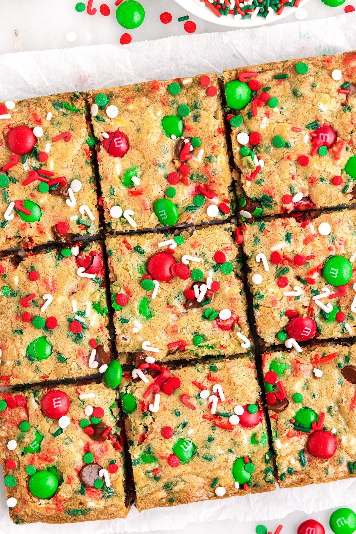 Christmas bar cookies cut into squares on parchment paper.