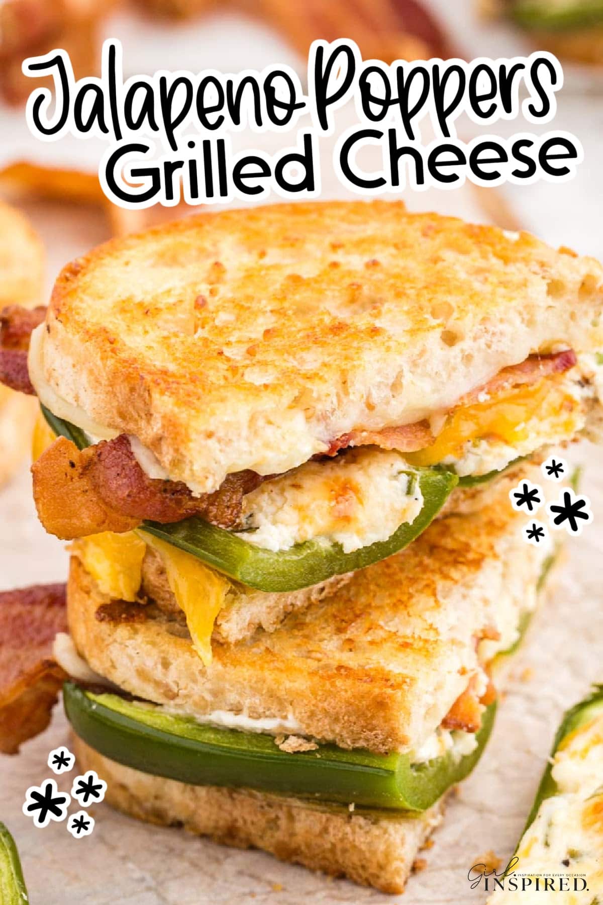 Two halves of a Jalapeno popper grilled cheese sandwich stacked on parchment paper-lined wooden kitchen board, stuffed jalapeno poppers, crispy bacon strips, on a white marble countertop.