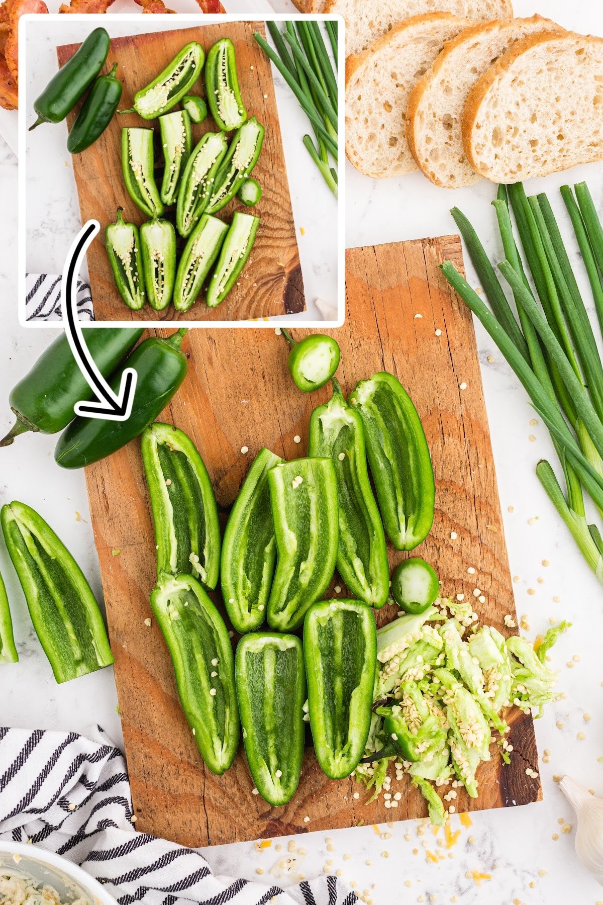 Jalapeño peppers cut in half and with seeds and stem removed on a cutting board.