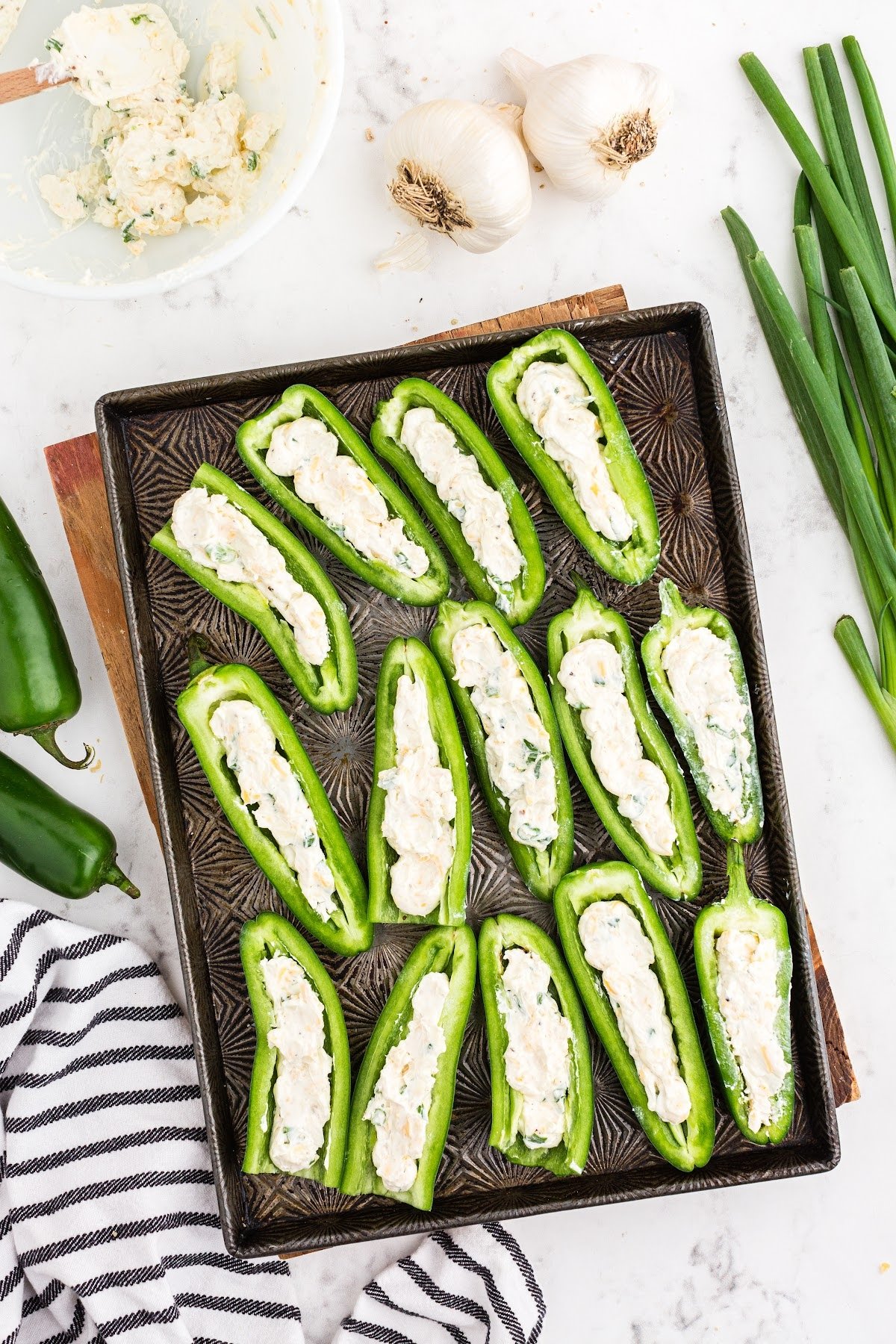 Jalapeno pepper halves filled with cream cheese mixture on baking sheet.