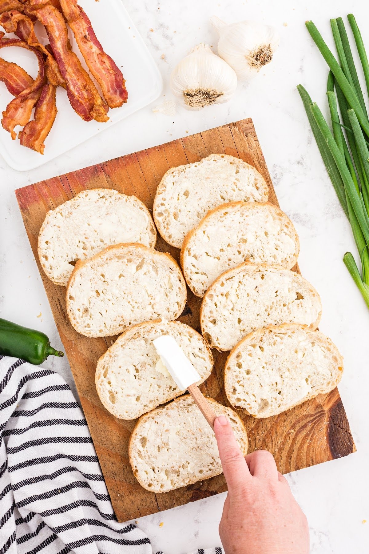 Spreading butter onto slices of sourdough bread set on a cutting board.